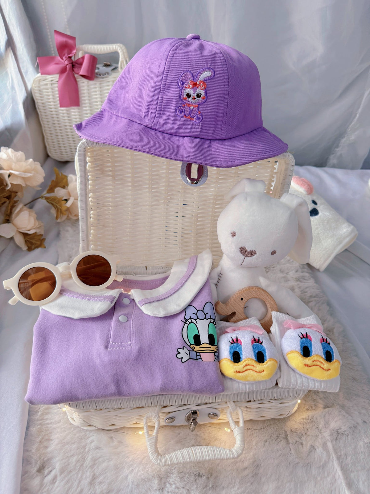 Little Daisy premium baby gift set in a rattan basket with lilac duck-collar romper with bucket hat