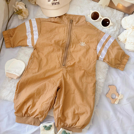 Flat lay view of Little Explorer baby hamper – sporty zip-up romper, sunglasses, matching hat, baby socks, towel bear and mittens