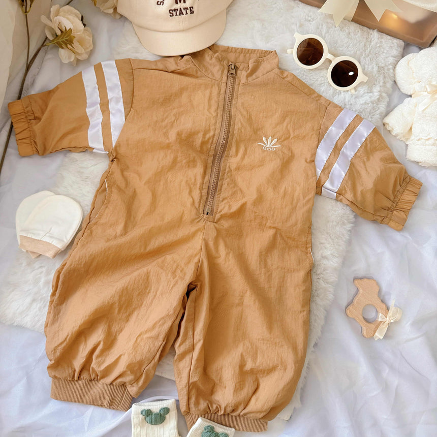 Flat lay view of Little Explorer baby hamper – sporty zip-up romper, sunglasses, matching hat, baby socks, towel bear and mittens
