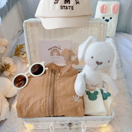Little Explorer premium baby hamper – plushie, teether, white rattan basket, sunglasses, matching hat, and baby socks