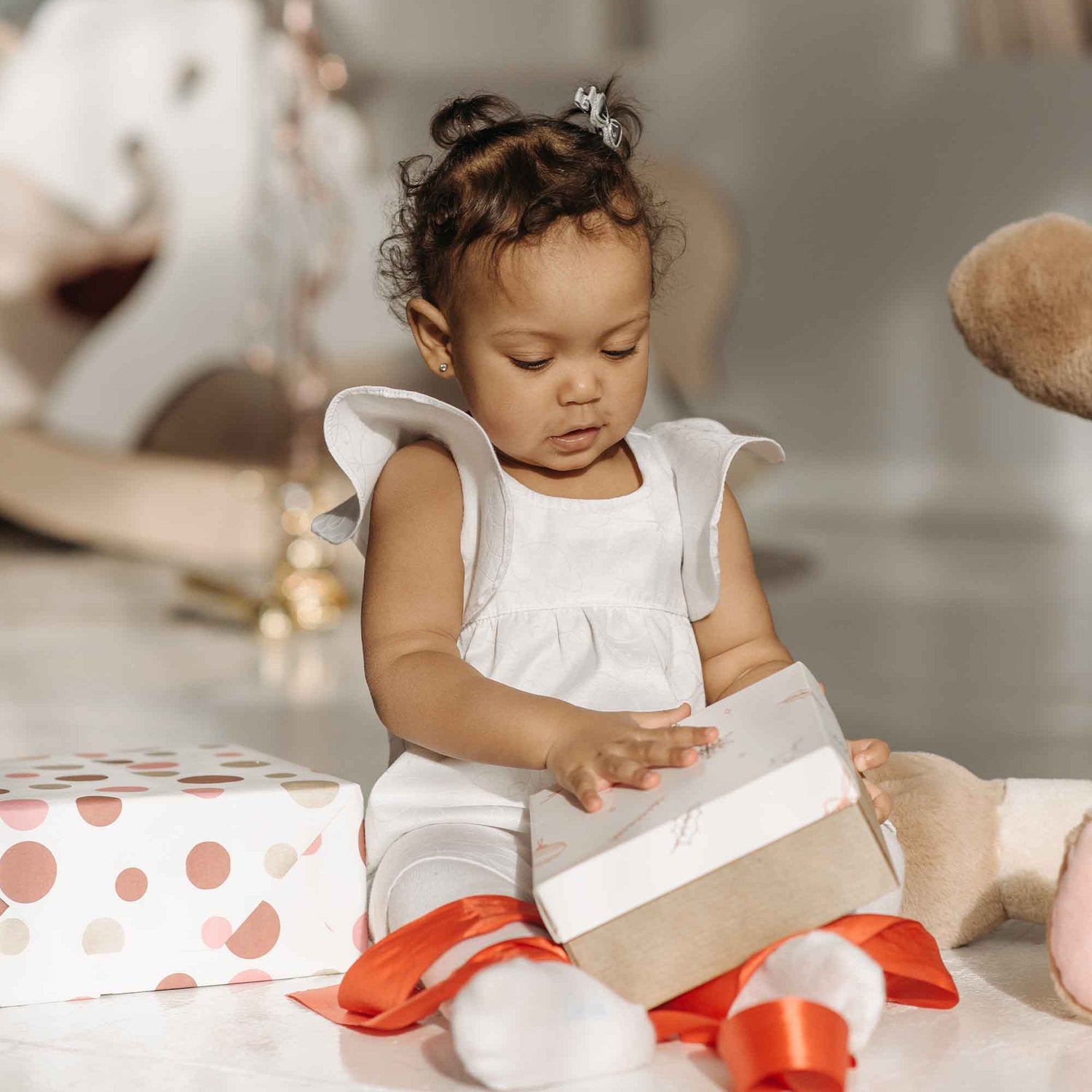 A baby girl opening a present box during her baby shower party.