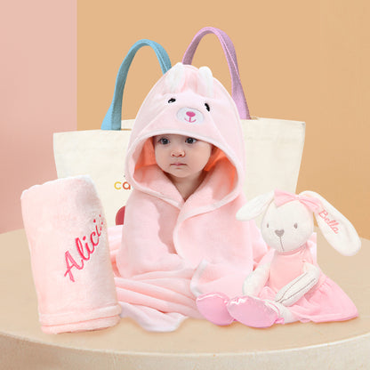 A newborn baby wearing a pink bunny hooded bath towel, accompanied by pink soft toys and a pink fleece blanket. The fleece blanket and soft toys have embroidered names. Displaying a delightful newborn baby hamper.