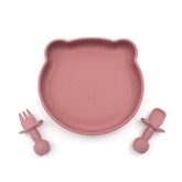 Pink BPA-free silicone plate shaped like a bear’s face, accompanied by matching fork and spoon, designed for babies.