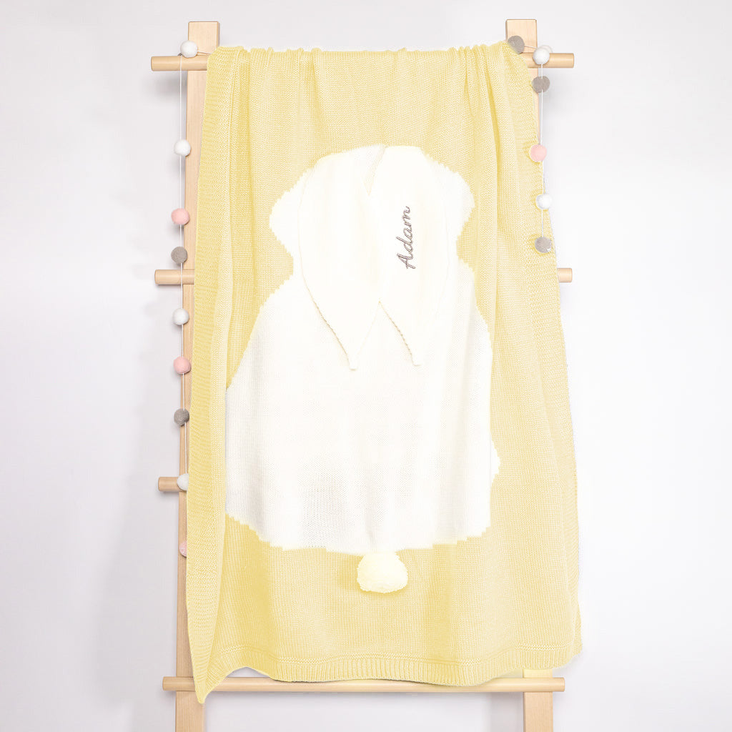 Yellow Knit Bunny blanket hanging on rack with baby&