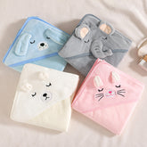 Four folded animal hooded bath towels displayed on a bed. The towels feature a blue dog, a grey elephant, a pink bunny, and a white bear.