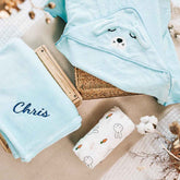 Light blue hooded towel with a cute puppy face, matching fleece blanket with ‘Chris’ embroidered, and a Miffy swaddle with bunny and carrot prints.