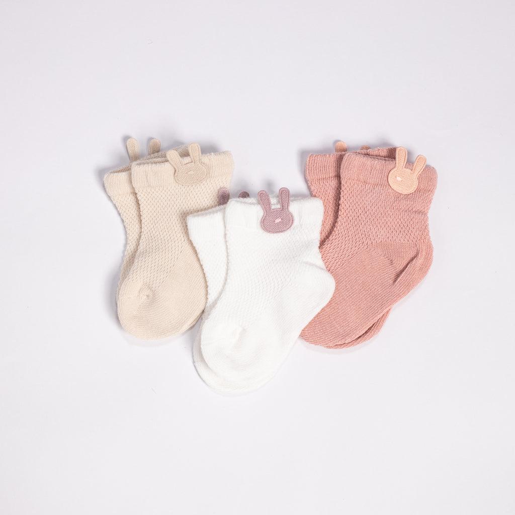 Three pairs of baby socks with bunny ears.