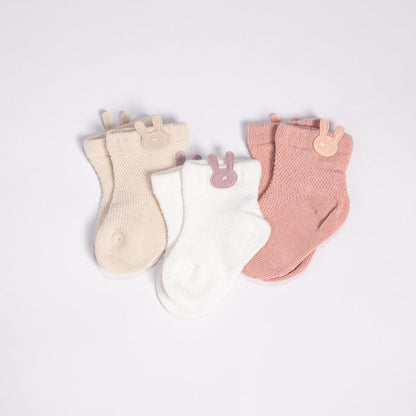 Three pairs of baby socks with bunny ears.