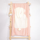 A pink and white baby towel with a hood, personalized with the name "Mia," hanging on a wooden rack with decorative knobs.