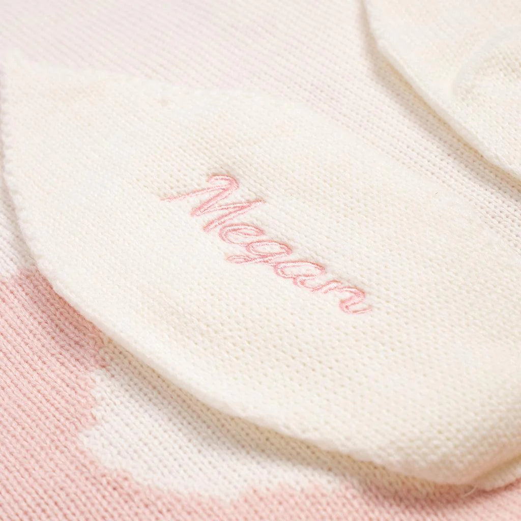 A white and pink knitted blanket with the name &quot;Megan&quot; embroidered on it.