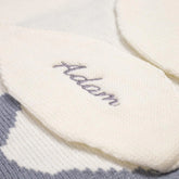 Close-up view of a white knitted baby blanket, showcasing the name &