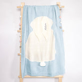 Personalized baby towel draped over a wooden rack, showcasing a delicate pastel blue color with a plush white hood featuring a playful pompom. The hood is elegantly embroidered with the name &