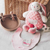 Pink bunny-themed baby dining set featuring a soft bunny plush teether, a BPA-free silicone plate with matching fork and spoon, and a personalized pink organic cotton bib.