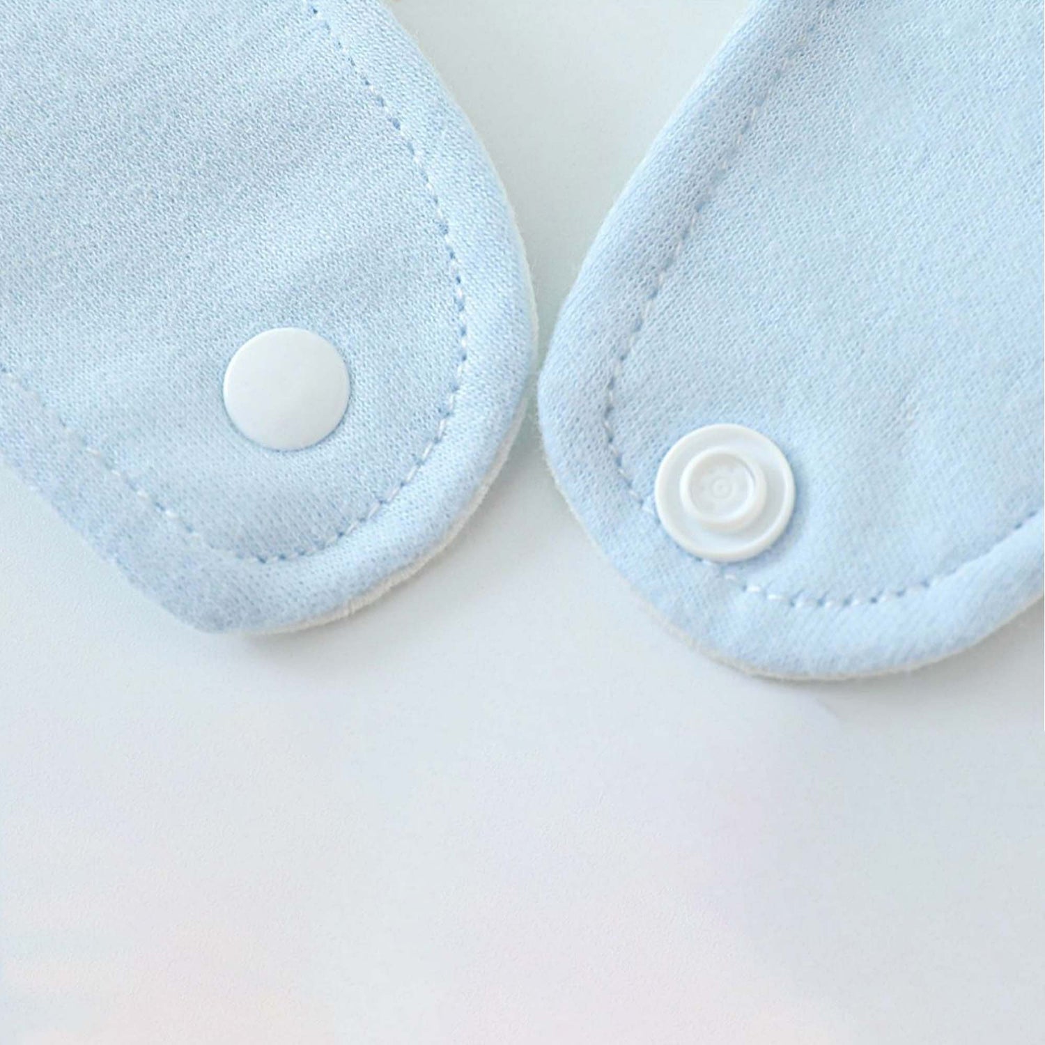 A close up of the blue cotton baby bib button