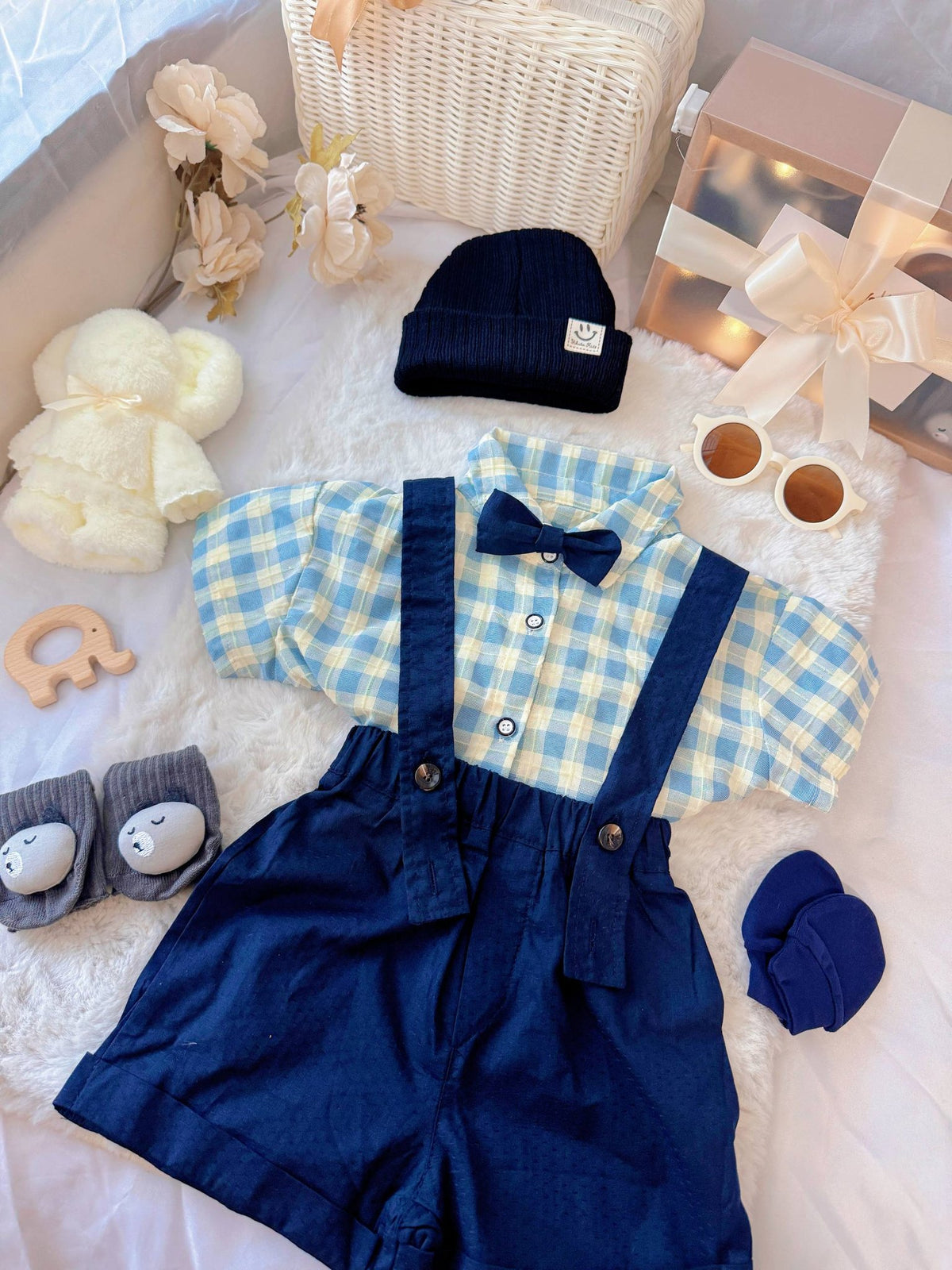 Charlie Boy baby outfit flat lay – blue gingham shirt with bow tie and suspender shorts