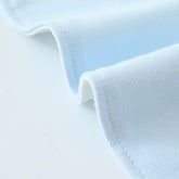 A close up of the blue cotton baby bib showing details