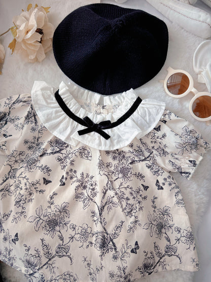 French Blossom baby outfit flat lay – floral romper with ruffled collar and black beret