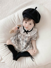 Baby wearing the French Blossom floral romper with ruffled collar and black beret