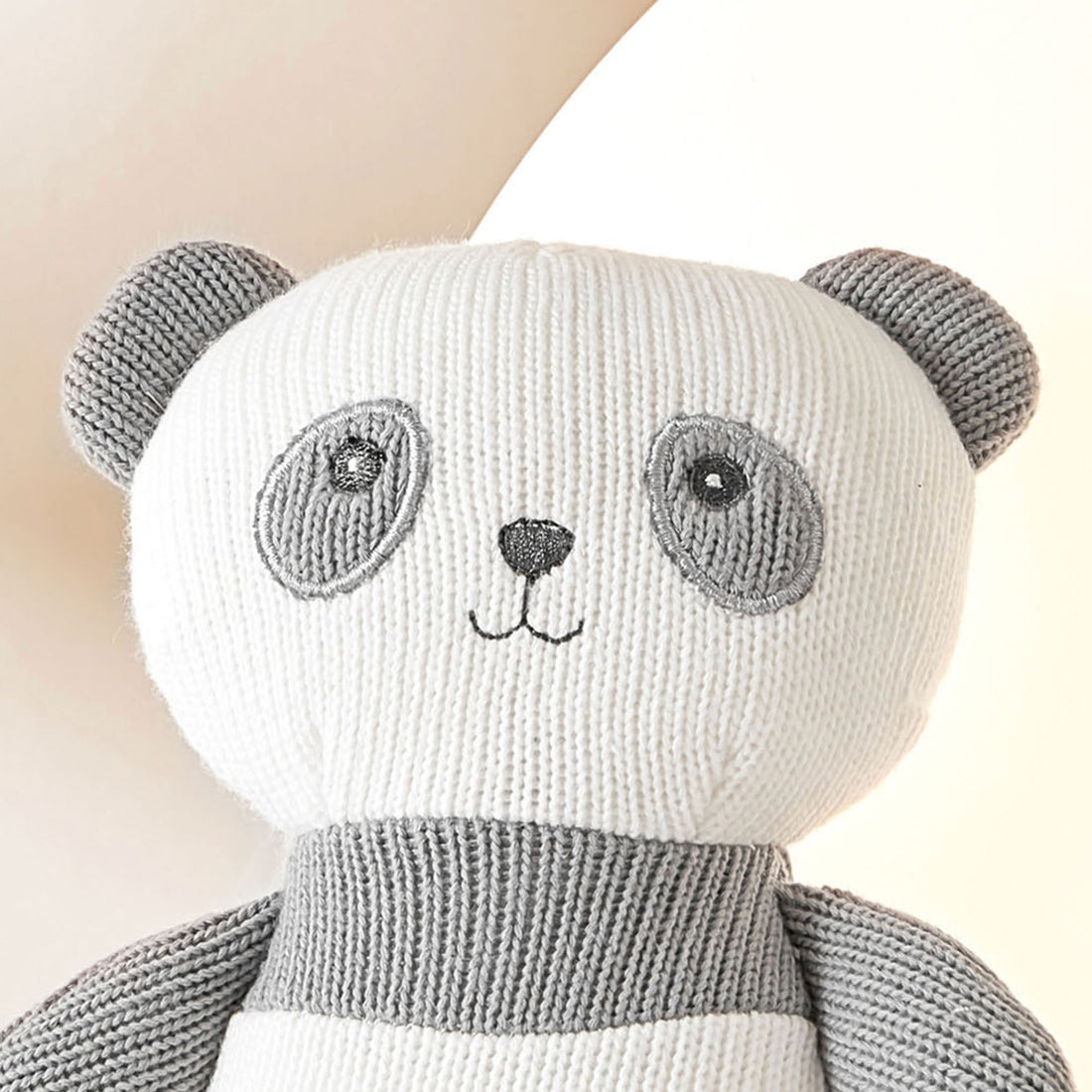 A close-up photo of a stuffed panda bear. The panda bear is made of soft, black and white fabric. It has round black eyes and a stitched black nose and mouth.