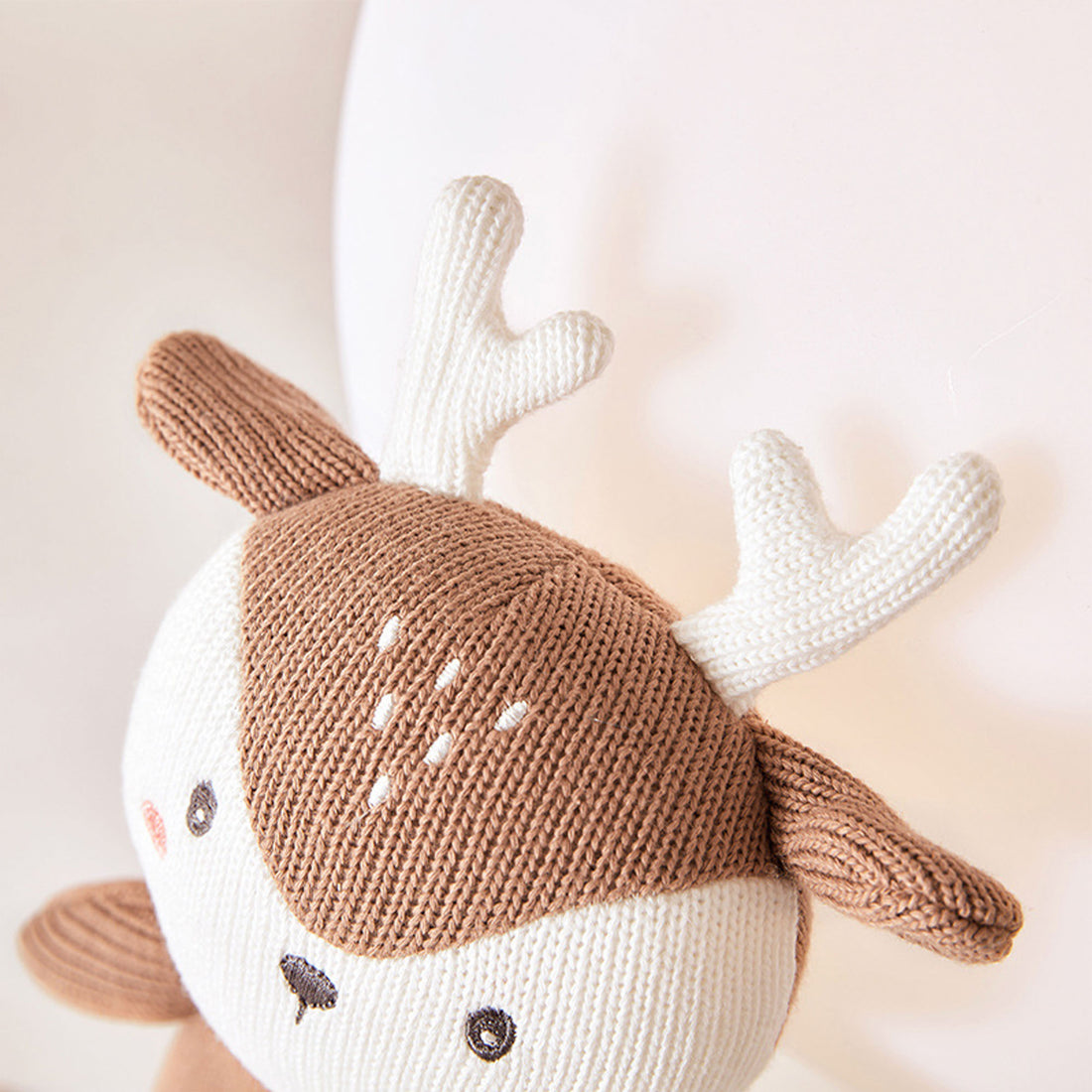 A close-up photo of a stuffed animal with white antlers. The stuffed animal appears to be a deer with brown fur and a white belly. It is sitting on a white background.