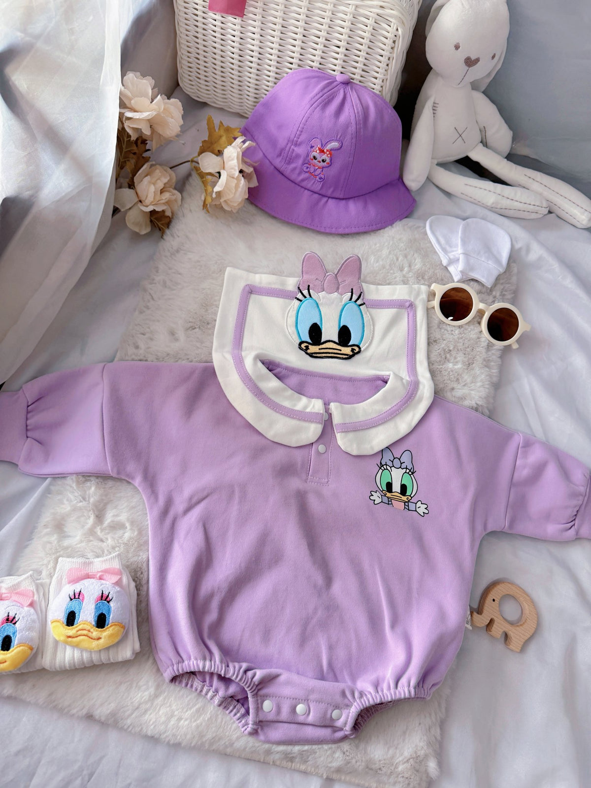 Little Daisy baby outfit flat lay – lilac duck-collar romper with bucket hat