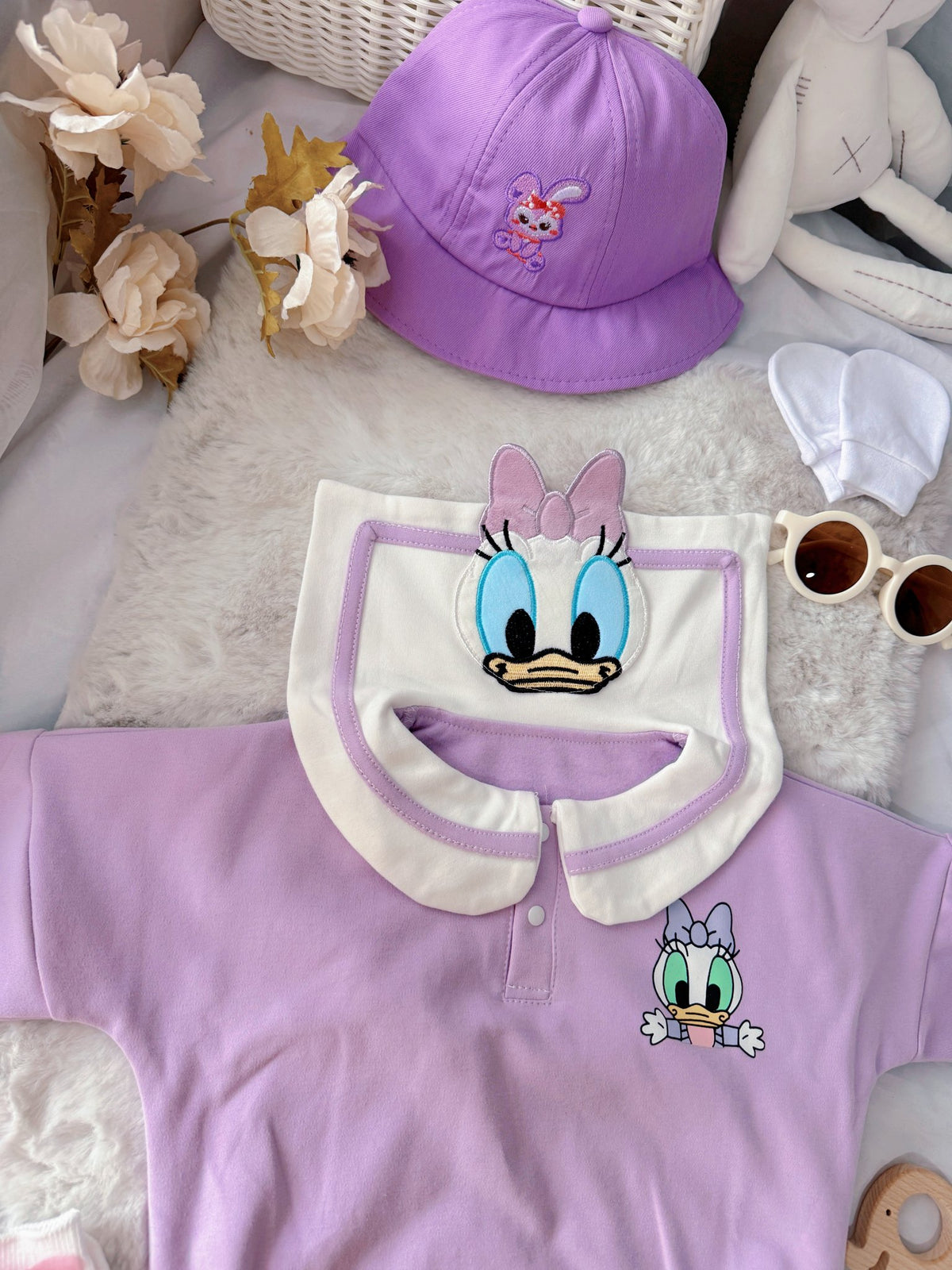 Little Daisy baby outfit flat lay – lilac duck-collar romper with bucket hat