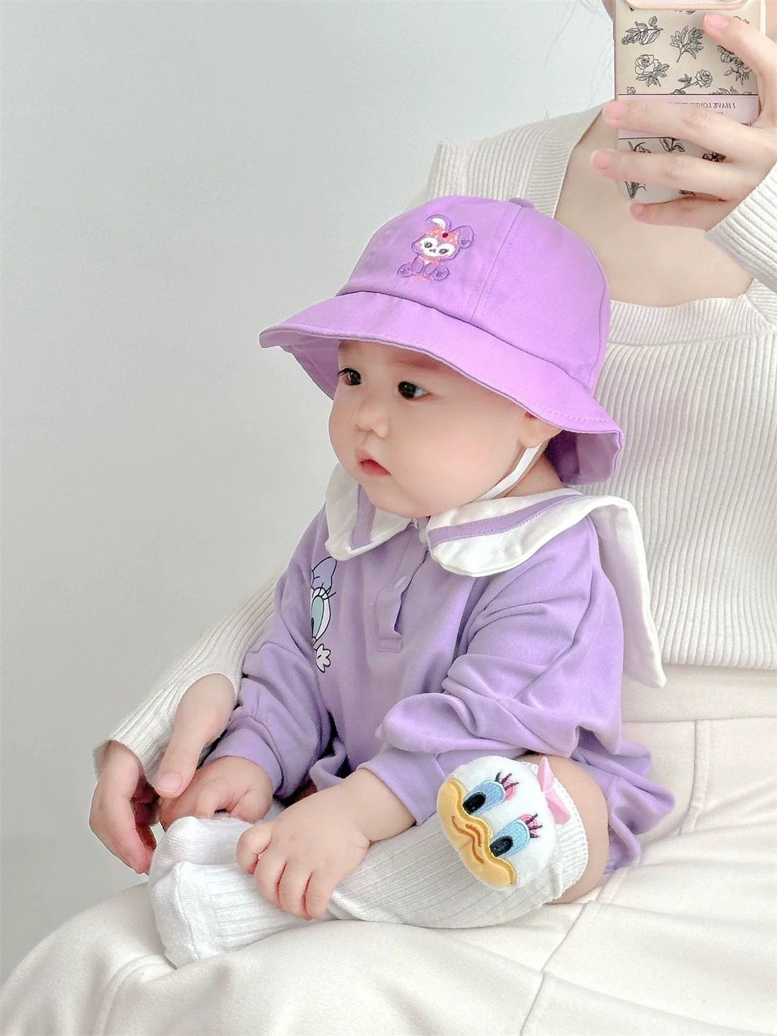 Baby wearing the Little Daisy lilac duck-collar romper with bucket hat