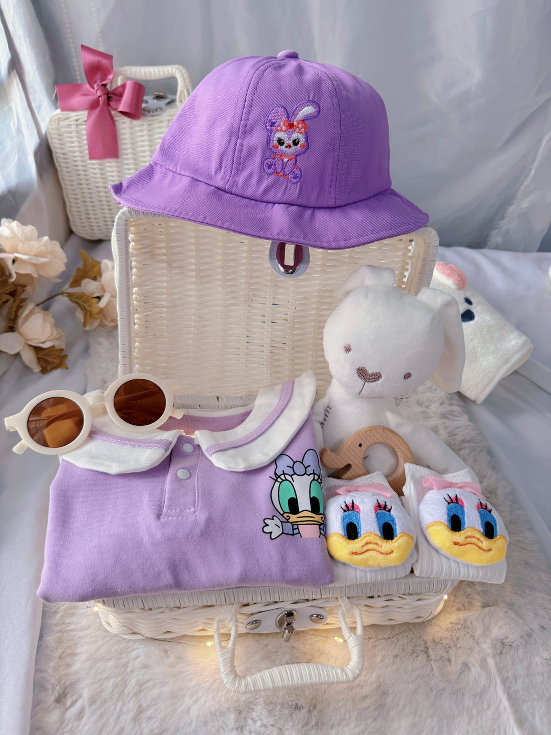Little Daisy premium baby gift set in a rattan basket with lilac duck-collar romper with bucket hat