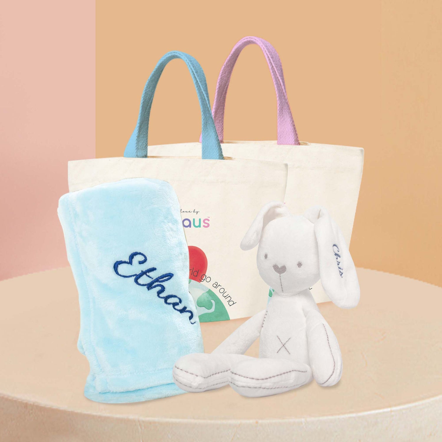 White Bunny Plushie displaying next to a blue fleece blanket, both with name embroidered.