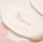A white and pink baby blanket with the personalised name "Megan" on it.