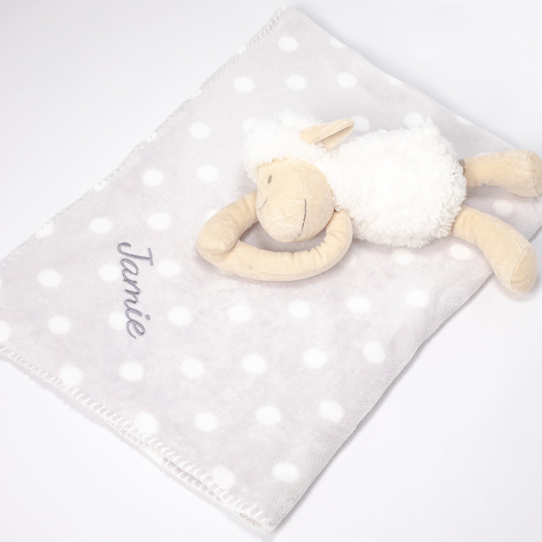 Sheep design blanket lying open flat with a plush sheep on top, showcasing the embroidered baby&